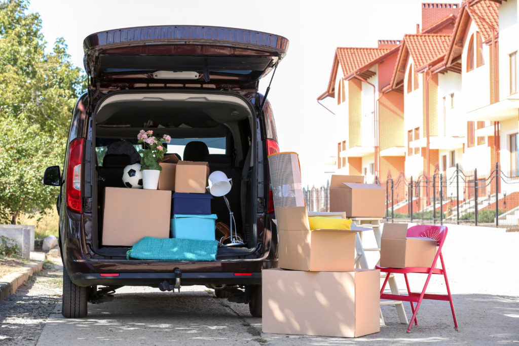 Cardboard boxes, furniture and car on city street. Moving into new house concept